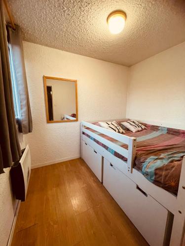 une petite chambre avec un lit et un miroir dans l'établissement T2 cosy, pieds des pistes 4 pers. centre station, à Les Deux Alpes