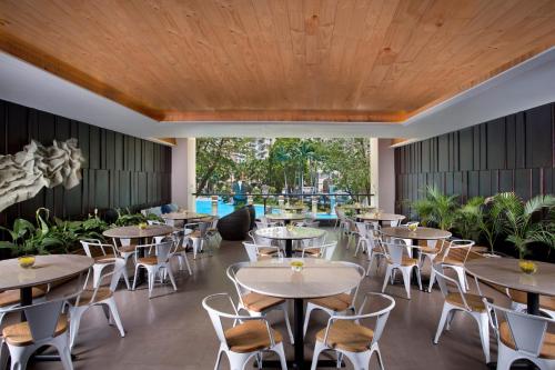 a restaurant with tables and chairs and a wooden ceiling at Ascott Waterplace Surabaya in Surabaya