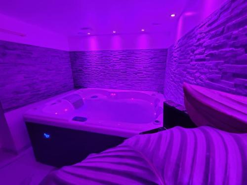 a purple room with a tub and a bed at Studio élégant l'orchidée Jacuzzi en intérieur toute l'année in Juvignac