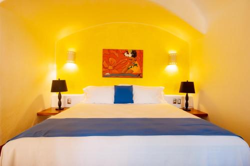 a bedroom with a large bed with a yellow wall at Ensueño de Fuga in Zihuatanejo