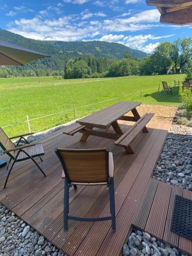 a wooden deck with a picnic table and a chair at Nassfeld Holiday Home in Rattendorf
