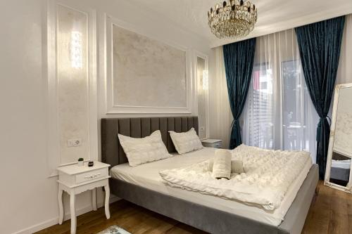 a bedroom with a white bed with a chandelier at Sika Onyx Garden Apartment - cazare Arad - self check-in in Arad