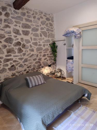 un lit dans une chambre avec un mur en pierre dans l'établissement La Porte Verte, à Capendu