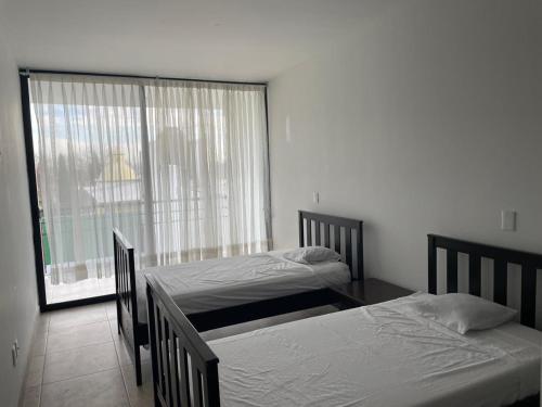 two beds in a room with a large window at Casa ocho in Oaxtepec