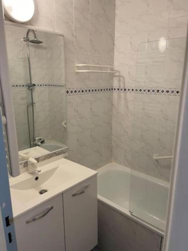 une salle de bain avec un lavabo, une baignoire et un miroir dans l'établissement Les Voiles du Port au CAP, au Cap d'Agde