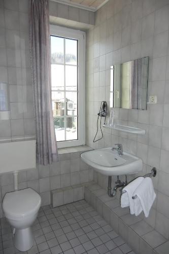 a white bathroom with a toilet and a sink at Gasthof Susewind in Antfeld