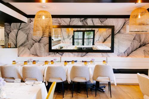 a dining room with white tables and chairs and a mirror at American Beech Hotel in Greenport