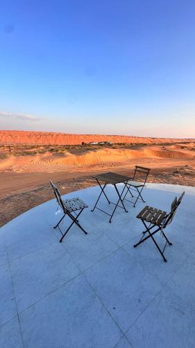 two chairs and a picnic table on top of a roof at Starry Domes Desert Camp in Badīyah