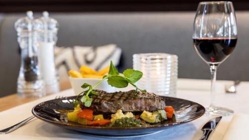 a steak on a plate with vegetables and a glass of wine at Holiday Inn Eindhoven Centre by IHG in Eindhoven