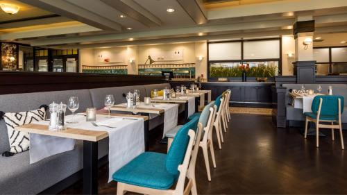 a restaurant with white tables and blue chairs at Holiday Inn Eindhoven Centre by IHG in Eindhoven