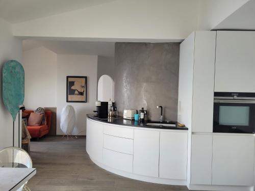 une cuisine avec des armoires blanches et un salon dans l'établissement Villa HELIADE -Ile du Levant, à Hyères