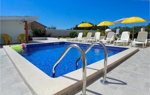 una piscina con sedie e ombrelloni su un patio di 3 Bedroom Beautiful Home In Muntic a Muntić