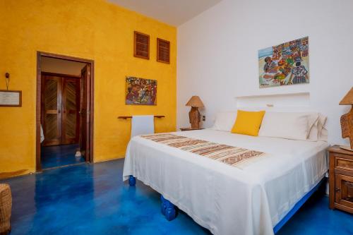 a bedroom with a large bed and a yellow wall at Ensueño de Fuga in Zihuatanejo