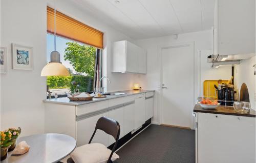 eine Küche mit weißen Schränken und einem Tisch und einem Fenster in der Unterkunft 3 Bedroom Cozy Home In Risskov in Risskov