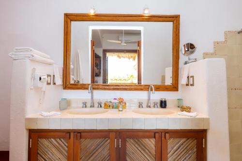 a bathroom with two sinks and a mirror at Ensueño de Fuga in Zihuatanejo