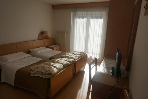 a bedroom with two beds and a television in it at Hotel & Residence Sylvanerhof in Chiusa