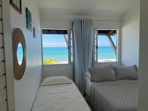 a bedroom with two beds and a view of the ocean at Casa duplex beira mar com caseiro de cortesia em Maceió in Maceió