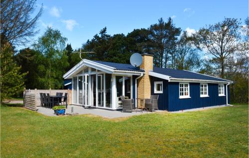 a small blue house on a grass field at Two-Bedroom Holiday Home In Ringkobing in Ringkøbing