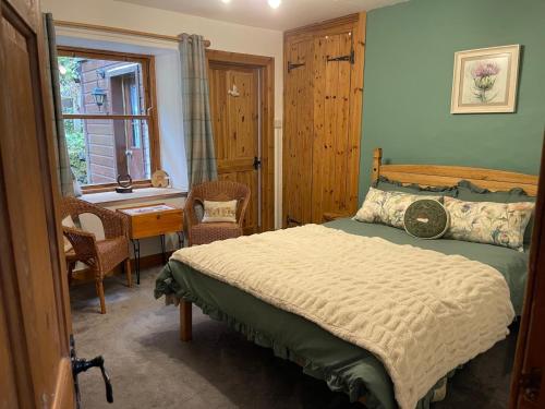 une chambre avec un lit, un bureau et une fenêtre dans l'établissement Yairbrig Cottage, à Galashiels
