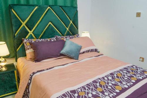 a bed with pillows on it in a room at Frade Apartment in Igbe Ewoliwo