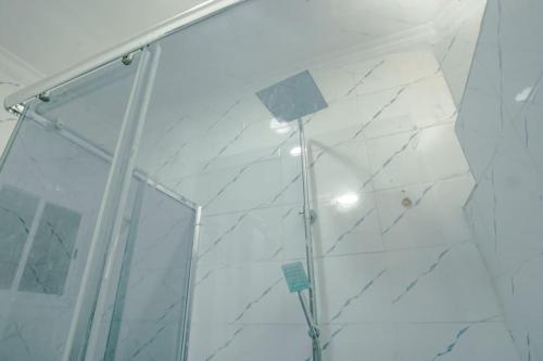 a shower with white marble walls and a glass door at Frade Apartment in Igbe Ewoliwo