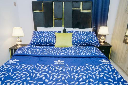 a bed with a blue comforter and a yellow pillow at Frade Apartment in Igbe Ewoliwo