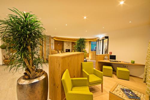 a living room with yellow chairs and a potted plant at Hotel Grüner Baum in Zell am See