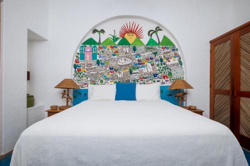 a bedroom with a white bed with a large headboard at Ensueño de Fuga in Zihuatanejo