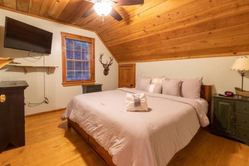 a bedroom with a large white bed with a television at Cozy Cabin Smoky Mountains - Hot tub, pool, & golf in Townsend