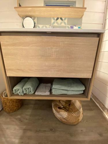 - une étagère en bois avec des serviettes et un panier dans l'établissement fleur de sel, à Sainte-Soulle