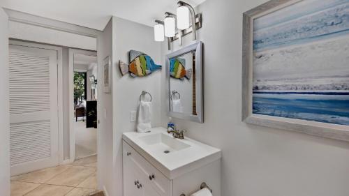 a white bathroom with a sink and a mirror at Conch in the Treetops by Last Key Realty in Key West