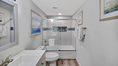 a white bathroom with a toilet and a sink at Conch in the Treetops by Last Key Realty in Key West
