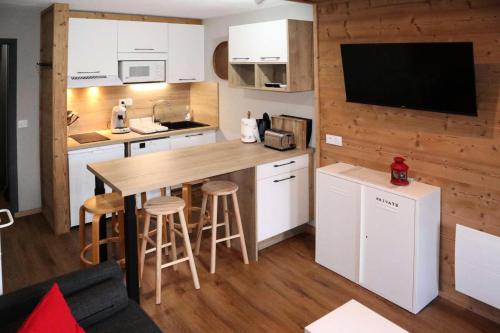 - une cuisine avec des placards blancs et un mur en bois dans l'établissement Résidence La Chamoisiere - Très joli studio entièrement refait MAE-5181, aux Orres