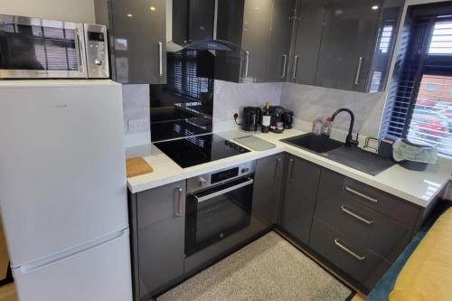 a kitchen with black cabinets and a white refrigerator at Town Centre Modern 1 Bed self-contained Apartment in Newbury