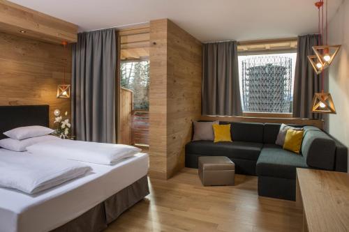 カチュベルクヘーエにあるFalkensteiner Aktiv & Familienhotel Cristalloのベッドとソファ付きのホテルルーム