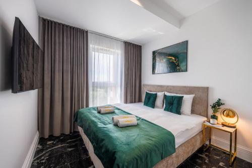a bedroom with a bed with a green blanket at Emihouse Riverside Premium Apartments & Free Parking in Rzeszów