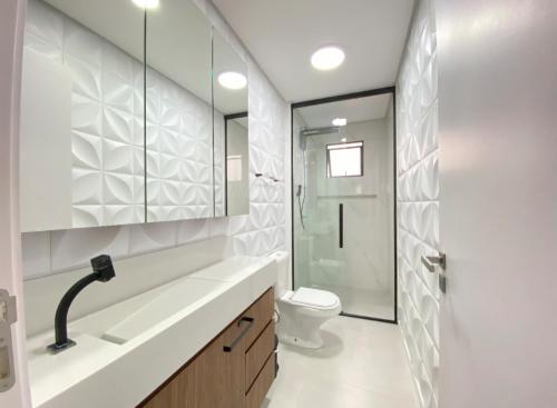 a white bathroom with a toilet and a sink at Apto mobiliado em Balneário Piçarras 100 m do mar in Piçarras