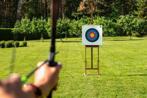 a person holding a bow and arrow in front of a target at Woodland Retreat Lodge in Vallapalu