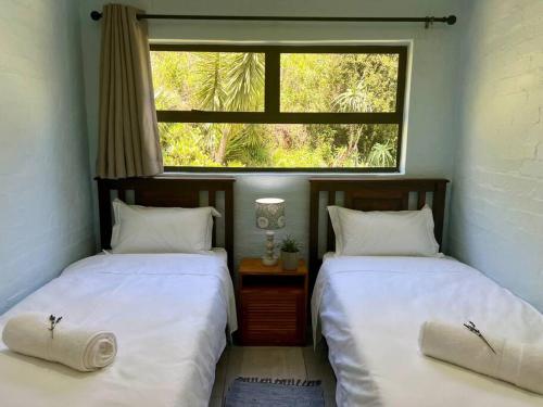 two twin beds in a room with a window at Berg Escape Poplar - Spacious Family Home in Bergview