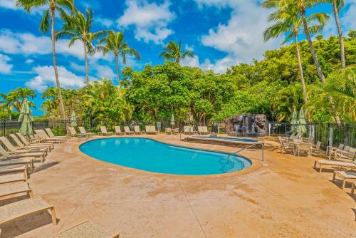 a swimming pool with chairs and palm trees at 1730 Kaleka 4 Bed Poipu House, Guest House walk to Beach in Koloa