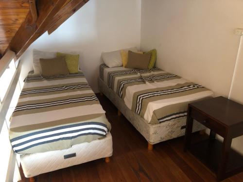two beds in a small room with a table at Ventanas al Mar in Villa Gesell