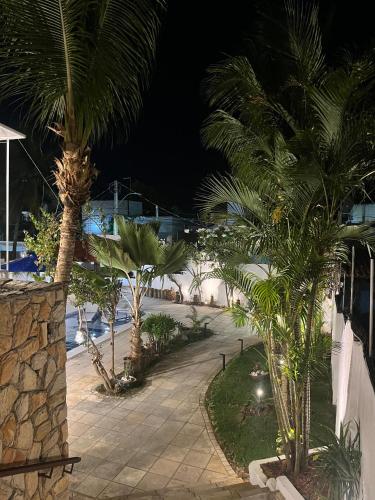 a walkway with palm trees in a resort at night at Residence Dunas Exclusive in Natal