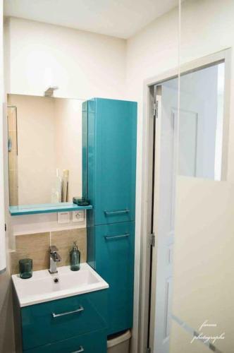 La salle de bains est pourvue d'une armoire bleue et d'un lavabo. dans l'établissement Studio vue Mer, à Palavas-les-Flots