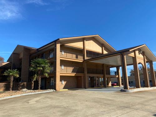 a large building with a parking lot in front of it at American Inn and Suites - Atlanta Airport Jonesboro I-75 in Jonesboro