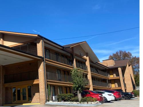 a building with cars parked in a parking lot at American Inn and Suites - Atlanta Airport Jonesboro I-75 in Jonesboro