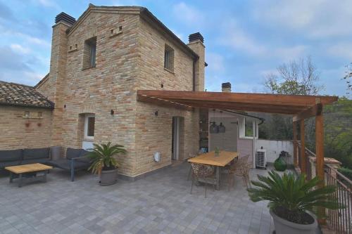 a patio with a brick building with a wooden pergola at The Cherry House, Apartamento Monterosa in Petritoli