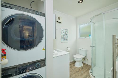 a bathroom with a washing machine and a toilet at Cosy Private Home in South Bay in Kaikoura