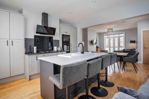 a kitchen with a sink and a counter with bar stools at Stylish & Spacious 3 Bed Apartment with Parking in Sheffield