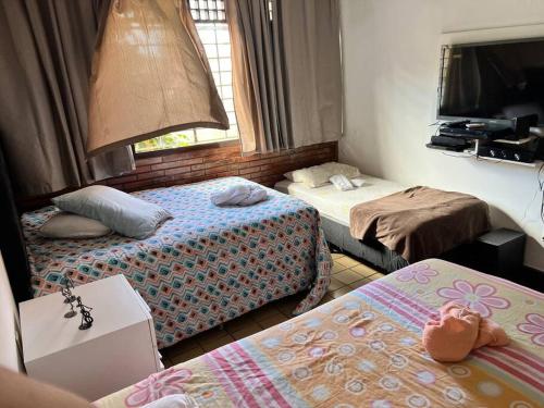 a hotel room with two beds and a tv at mansão com churrasqueira sinuca piscina aquecida in Natal