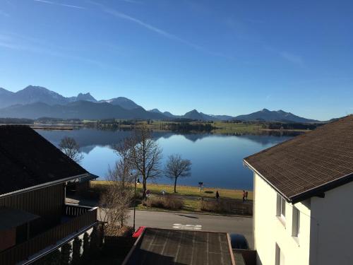 einen Blick auf einen See mit Bergen im Hintergrund in der Unterkunft Ferienwohnungen Hopfensee in Füssen